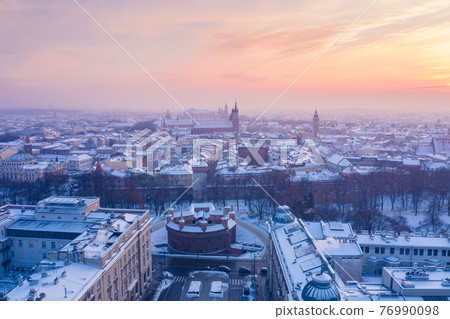 Barbikan and Krakow Old Town in winter. Snow on roofs in winter Krakow Poland at sunset Barbikan and Krakow Old Town in winter. Snow on roofs in winter Krakow Poland at sunset 76990098