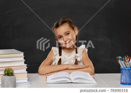 little child girl reading a book in the classroom 76990316