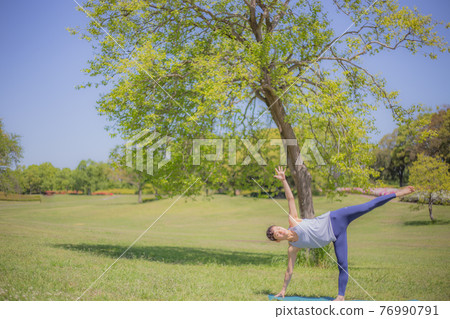 Woman doing yoga in front of a tree Woman doing yoga in front of a tree 76990791