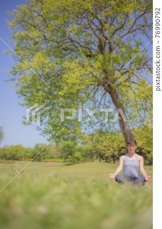 Woman doing yoga in front of a tree Woman doing yoga in front of a tree 76990792