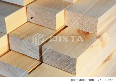 The wooden bars are stacked in a stack. Sawing drying and marketing of wood. Industrial background. The wooden bars are stacked in a stack. Sawing drying and marketing of wood. Industrial background. 76990868