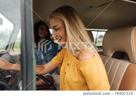 Side view of a blond woman on driver seat in a camper van Side view of a blond woman on driver seat in a camper van 76991319