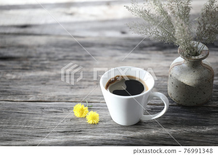 Small white coffee cup and and flowers on grey wooden table Small white coffee cup and and flowers on grey wooden table 76991348