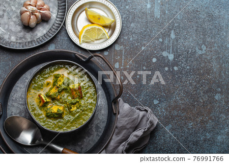 Indian dish Palak Paneer in bowl on rustic stone table copy space Indian dish Palak Paneer in bowl on rustic stone table copy space 76991766