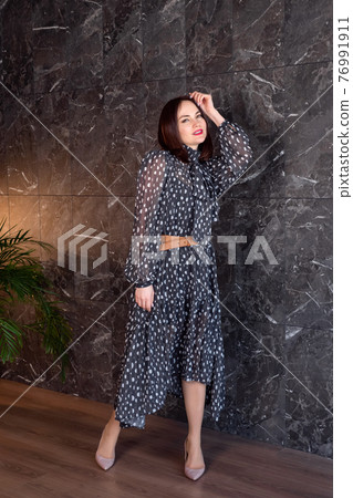 Beautiful woman in a black and white light flowing dress with polka dots Beautiful woman in a black and white light flowing dress with polka dots 76991911