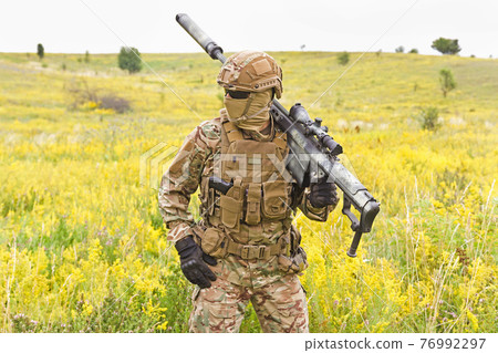 Soldier in a special military uniform with sniper rifle in the field 76992297