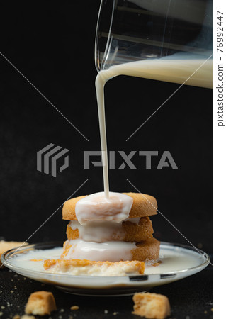 Cookies being topped with milk. Cookies being topped with milk. 76992447
