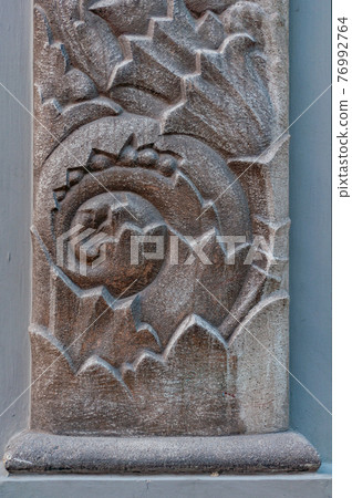 Close-up beautiful vegetable bas-relief on granite column, rough texture old-fashioned stone, declarative wall decoration building 76992764
