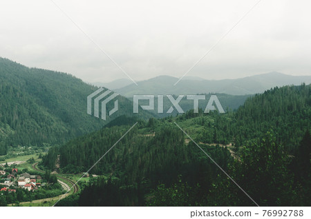 Colorful view from top hill to outskirts city near which winding railway is laid between hills and mountains 76992788