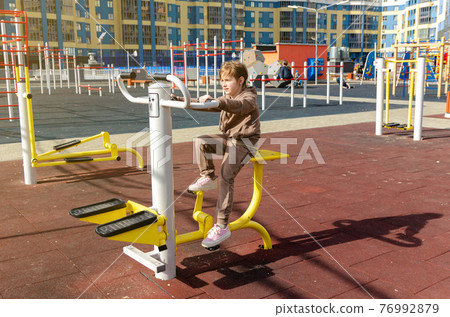 Adorable little kid girl making exercises on sports training apparatus at the gym 76992879