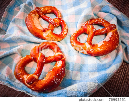Three delicious bavarian pretzels at table, top view Three delicious bavarian pretzels at table, top view 76993261