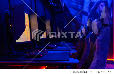Inside of illuminated internet cybercafe 76994262