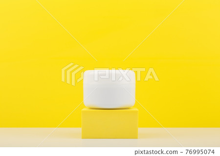 White cosmetic jar on yellow pedestal against yellow background with copy space White cosmetic jar on yellow pedestal against yellow background with copy space 76995074