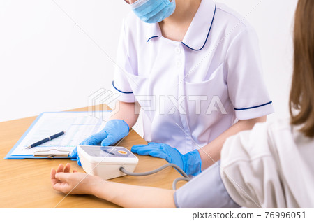 A nurse measuring a patient's blood pressure 76996051