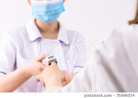 A nurse measuring saturation with a pulse oximeter A nurse measuring saturation with a pulse oximeter 76996054