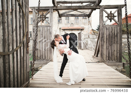 Beautiful romantic wedding couple of newlyweds hugging near old castle Beautiful romantic wedding couple of newlyweds hugging near old castle 76996438