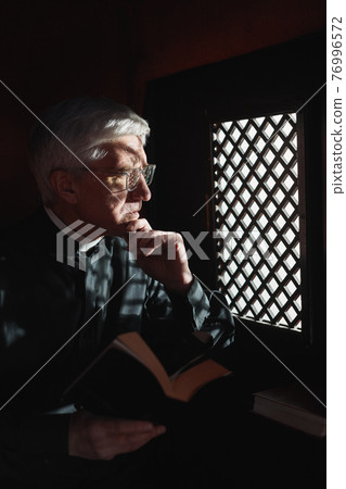 Priest with Bible in confessional Priest with Bible in confessional 76996572