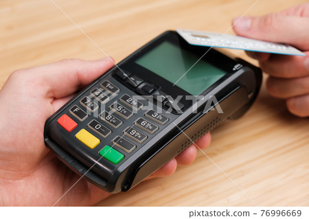 Close up man hand paying with contactless credit card with NFC technology using wireless payment terminal. Cashless payment during pandemic of coronavirus  76996669