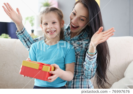 Woman and girl rejoice at surprise in gift box 76997676