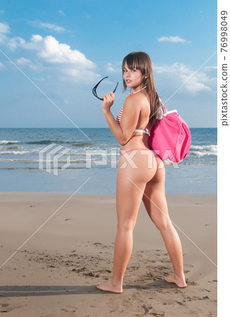 pretty young woman in bikini on the seashore at the beach pretty young woman in bikini on the seashore at the beach 76998049