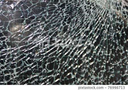 Texture of broken glass on dark background. Closeup 76998713
