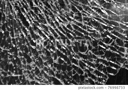 Black-and-white Texture of broken glass on dark background. Closeup 76998733