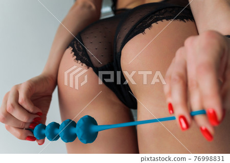 beautiful girl in sexy clothes holding in her hands a sex toy for adults. 76998831