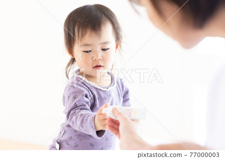 Mom putting moisturizing cream on her child 77000003