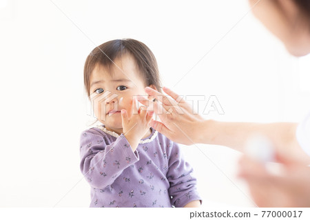 媽媽給她的孩子塗上保濕霜 77000017