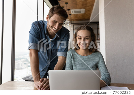 Happy man and woman colleagues cooperate on laptop 77002225