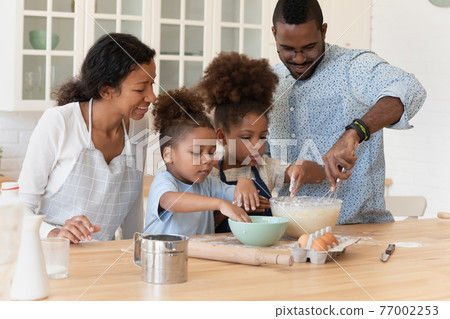 Happy couple of parents and kids baking homemade dessert together Happy couple of parents and kids baking homemade dessert together 77002253