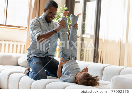 Happy dad holding legs of excited preschooler son Happy dad holding legs of excited preschooler son 77002376
