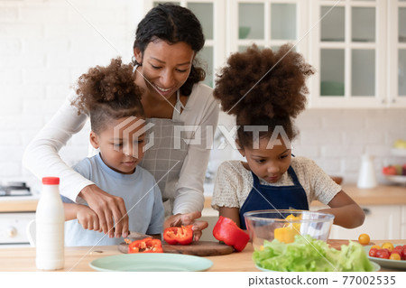 Happy mom teaching two preschooler kids to make vegetarian meal Happy mom teaching two preschooler kids to make vegetarian meal 77002535