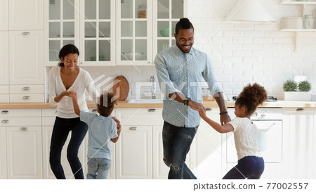 Happy African American parents and two kids dancing to music 77002557