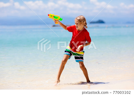 Child with toy water gun. Kids vacation beach fun. Child with toy water gun. Kids vacation beach fun. 77003102