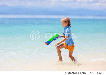 Child with toy water gun. Kids vacation beach fun. Child with toy water gun. Kids vacation beach fun. 77003328