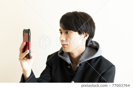 Male student looking at a smartphone 77003764