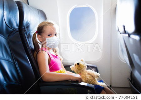 Child in airplane in face mask. Virus outbreak. Child in airplane in face mask. Virus outbreak. 77004151