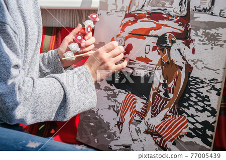 Female hands coloring canvas Picture by numbers car and girl. Creative hobby. Painting for beginners. Leisure activity for stay home isolation, anti-stress idea. Meditation, relax concept 77005439