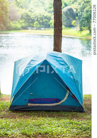 Camping under the forest, blue tent near lake. Outdoor travel, trip and vacation concept Camping under the forest, blue tent near lake. Outdoor travel, trip and vacation concept 77006126