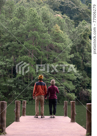 Happy couple traveler standing and looking Nature view, tourists in sweater traveling at Pang Oung, Mae Hong Son, Thailand. Together, travel, trip and vacation concept Happy couple traveler standing and looking Nature view, tourists in sweater traveling at Pang Oung, Mae Hong Son, Thailand. Together, travel, trip and vacation concept 77006279