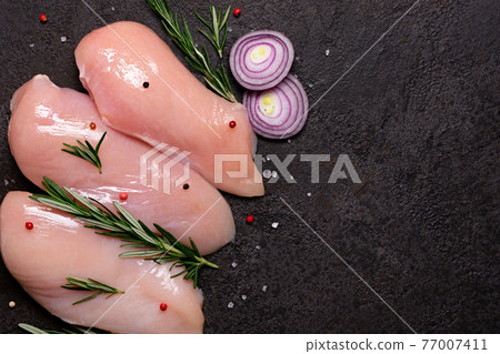Raw chicken breast with spices and herbs on black stone background. Preparation for cooking 77007411