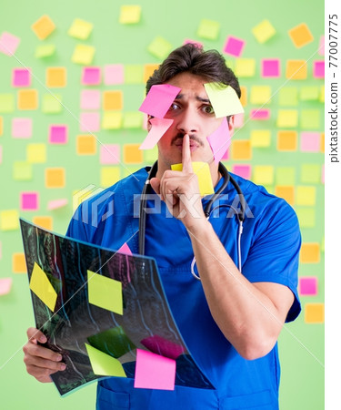 Young doctor with many reminders and urgent work 77007775