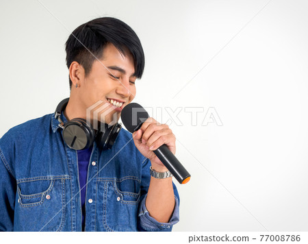 Young asian man in blue jean singing with microphone. Portrait on white background with studio light. Close Up Young asian man in blue jean singing with microphone. Portrait on white background with studio light. Close Up 77008786