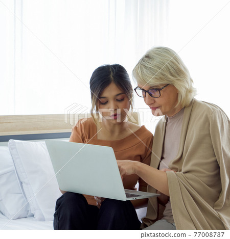 Asian daughter teach her adopted caucasian mother how to surf the Internet from a laptop computer. Happy mix skin family living together. Asian daughter teach her adopted caucasian mother how to surf the Internet from a laptop computer. Happy mix skin family living together. 77008787