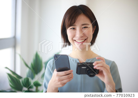 Woman with smartphone and compact digital camera 77010923