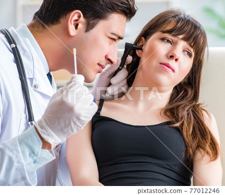 Doctor checking patients ear during medical examination 77012246