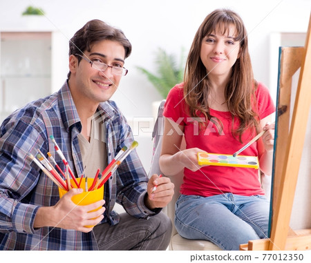 Artist coaching student in painting class in studio 77012350