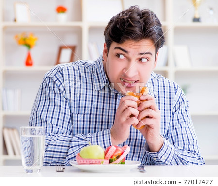 Man having dilemma between healthy food and bread in dieting con 77012427