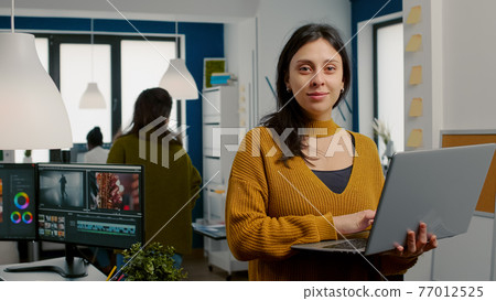 Woman retoucher looking at camera smiling working in creative media agency 77012525